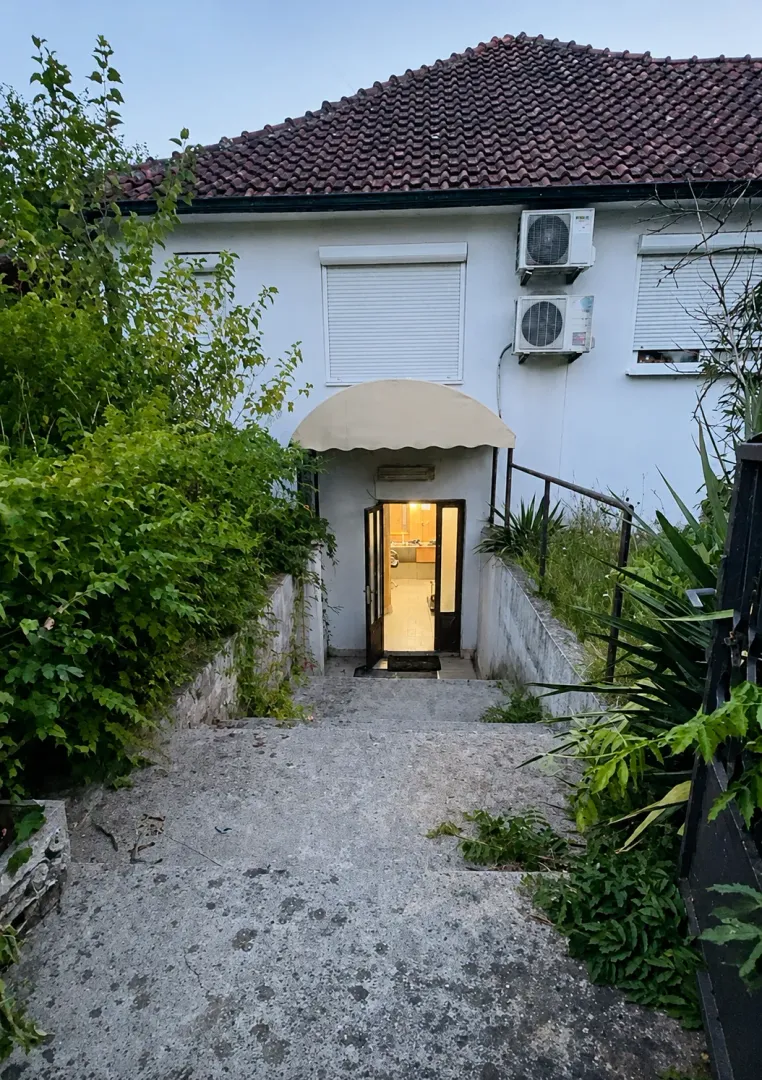Ulaz u kuću sa spoljnim stepeništem i zelenilom.