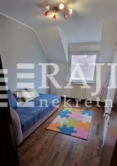 Dečja soba sa krevetom i šarenim tepihom.