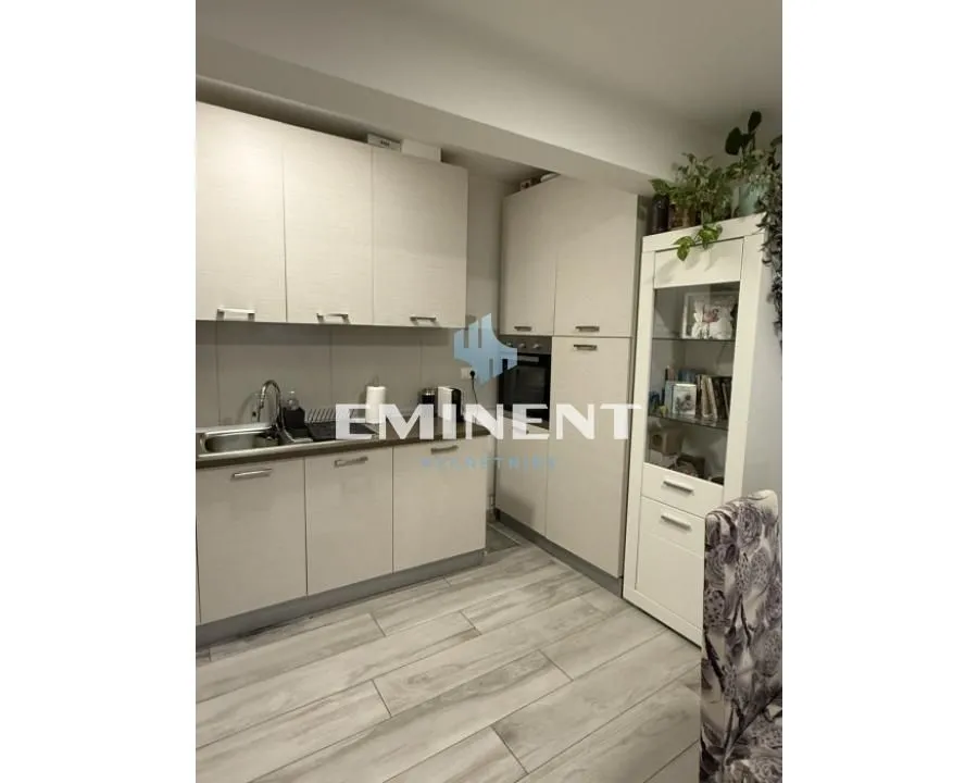 Kitchen with light wood cabinets and white display units.