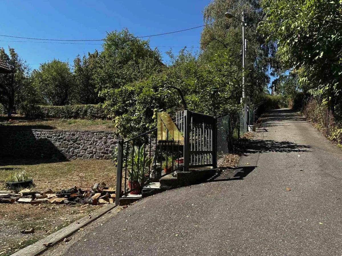 Prilaz dvorištu sa kapijom i uskom asfaltiranom ulicom pored.