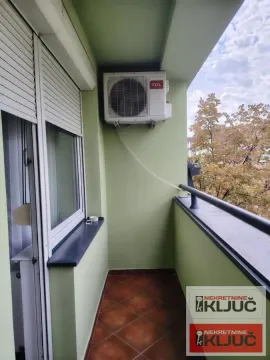 Manji balkon sa spoljnom jedinicom klima uređaja i pogledom na zelenilo. - image 6