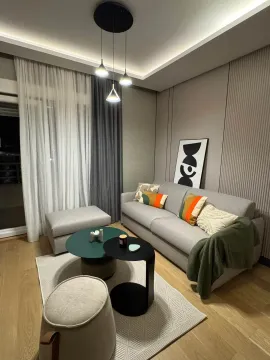 Modern living room with a gray sofa, coffee tables, and lighting. - image 2