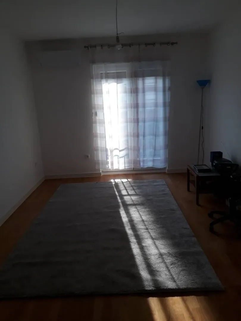 Empty room with a large rug and balcony doors.