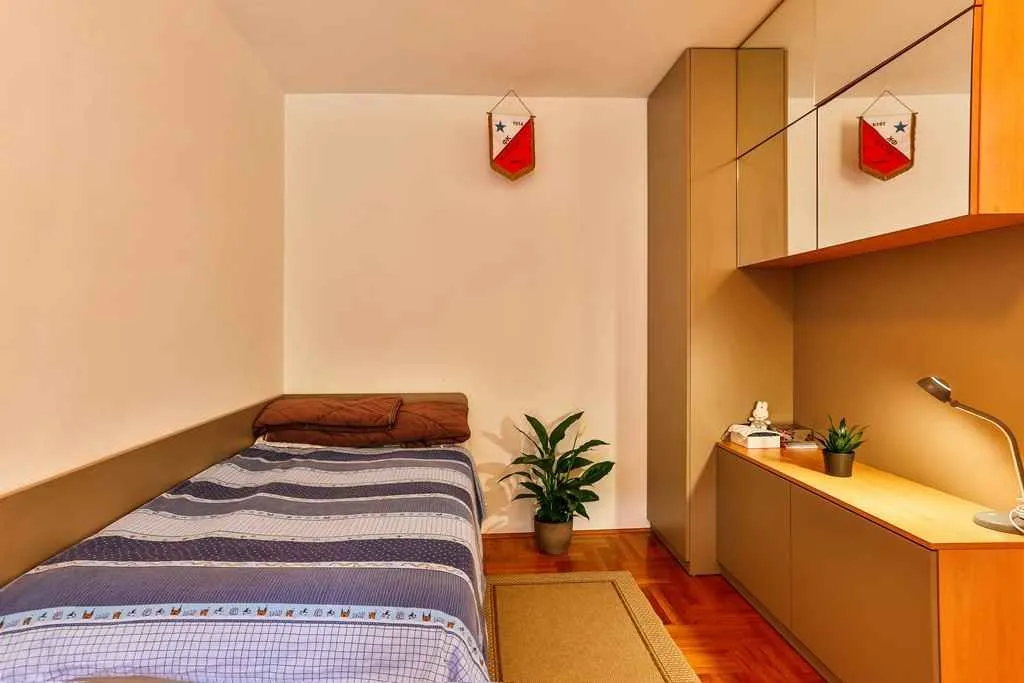 A simple bedroom with a single bed and a built-in wardrobe.