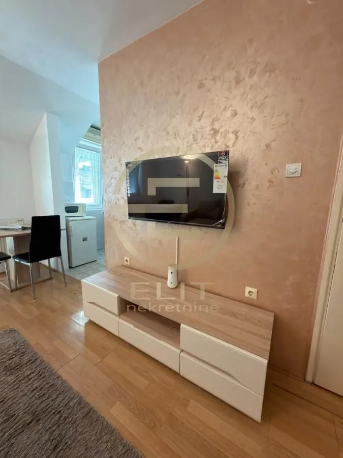 Dnevni boravak sa TV komodom i montiranim televizorom na zidu.