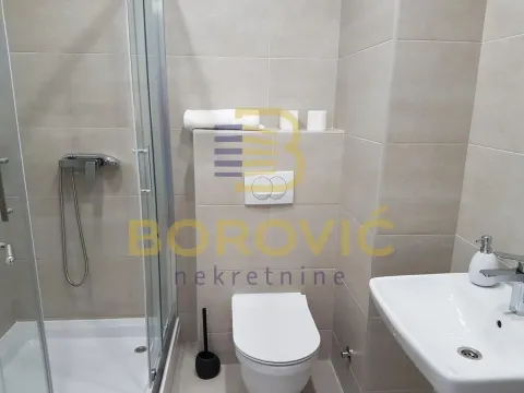 Modern bathroom with a shower cabin, washbasin, and toilet in beige tiles. - image 13
