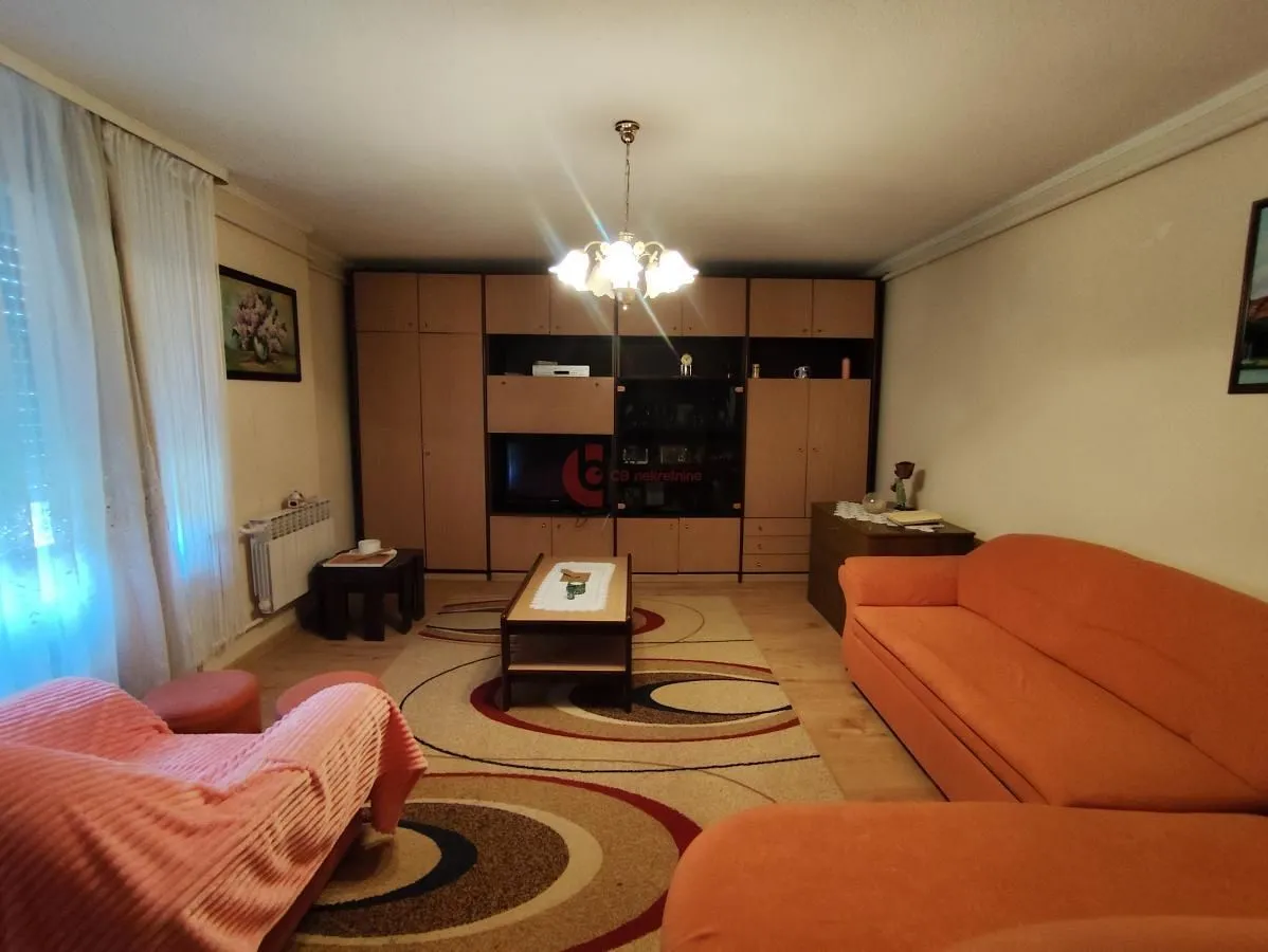 Living room with a sofa set, large wardrobe, and rug.