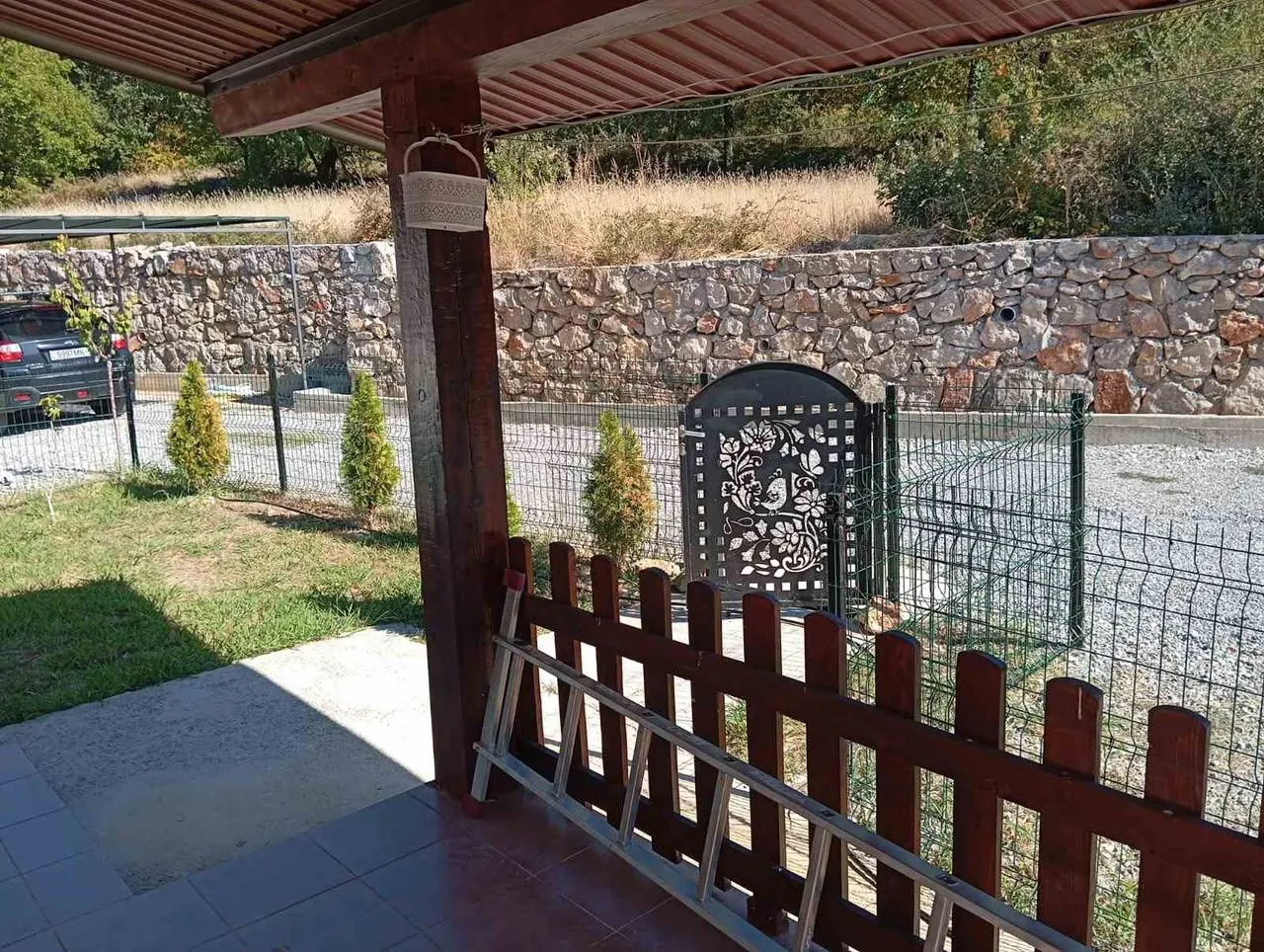 View from the covered terrace onto the yard and stone wall.