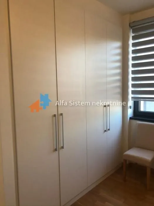 Large white built-in wardrobe in a room with a window and a chair.