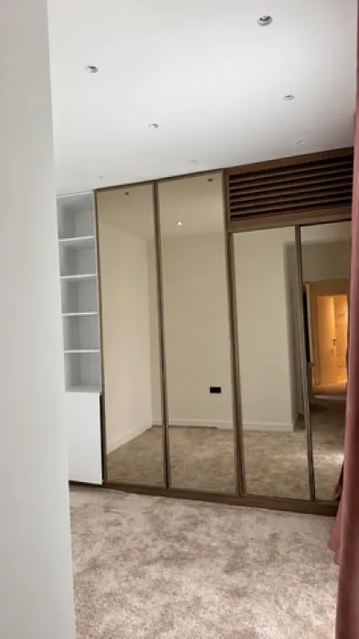 Bedroom with a large built-in wardrobe with mirrored doors.