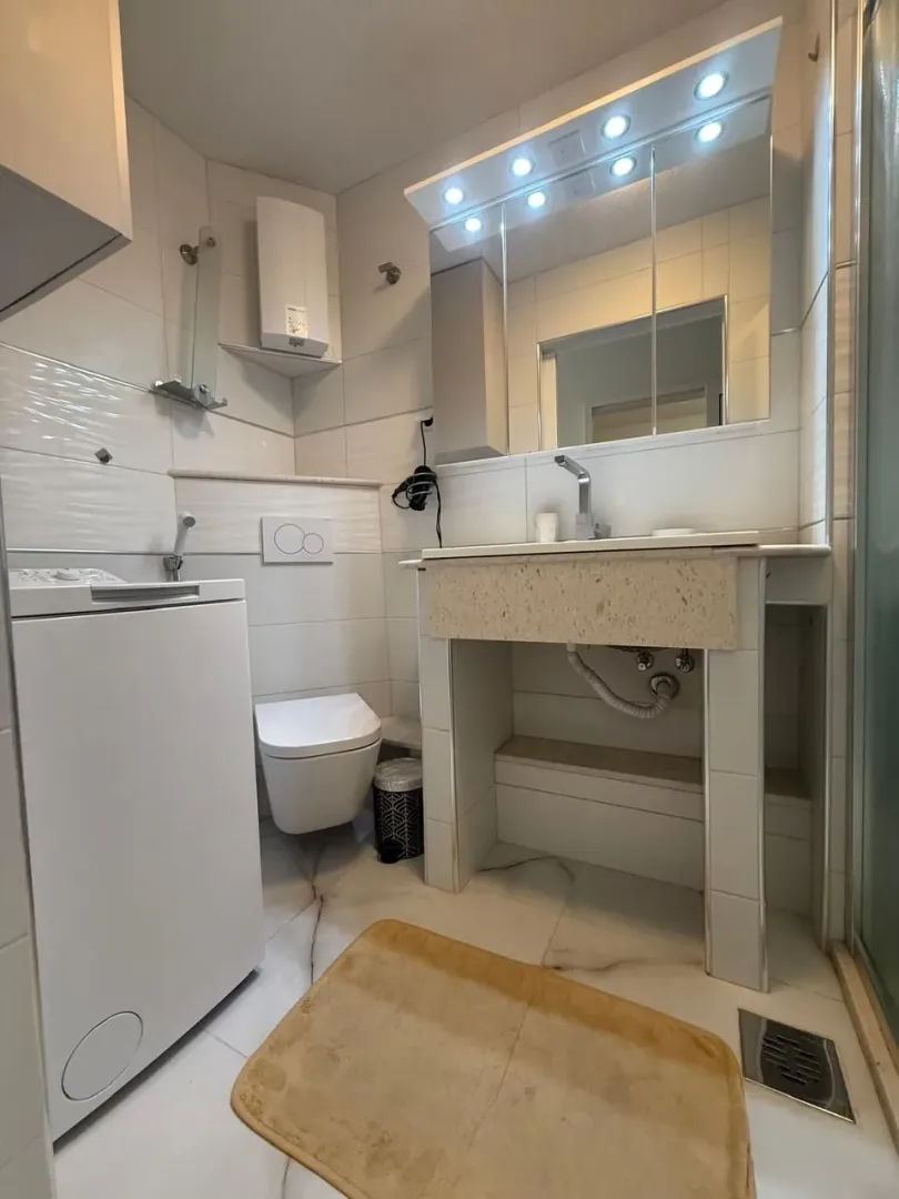 Kompaktno kupatilo sa umivaonikom, WC šoljom, tuš kabinom i mašinom za veš.