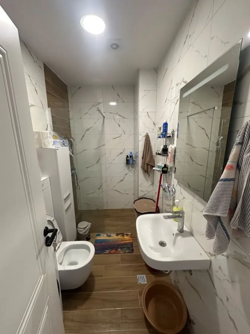 Bathroom equipped with a washbasin, toilet, and a glass-enclosed walk-in shower.