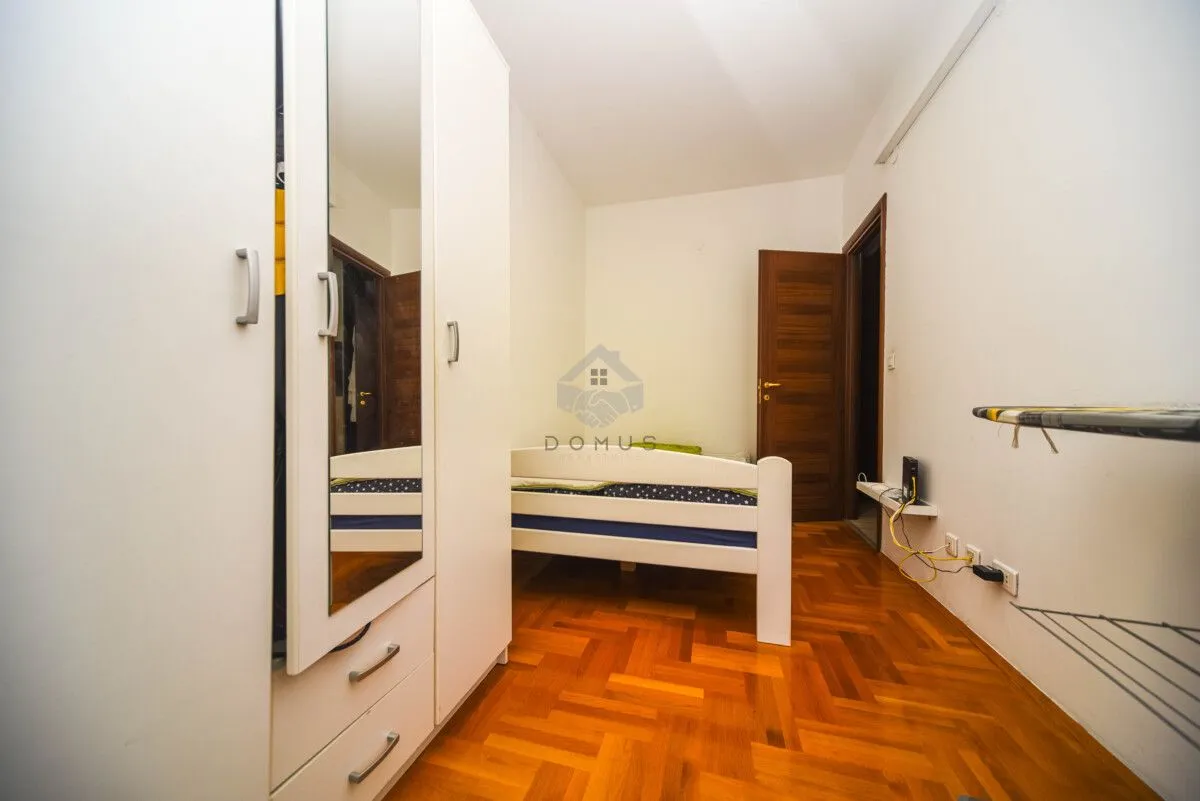 Manja spavaća soba sa krevetom i bijelim garderoberom sa ogledalom.