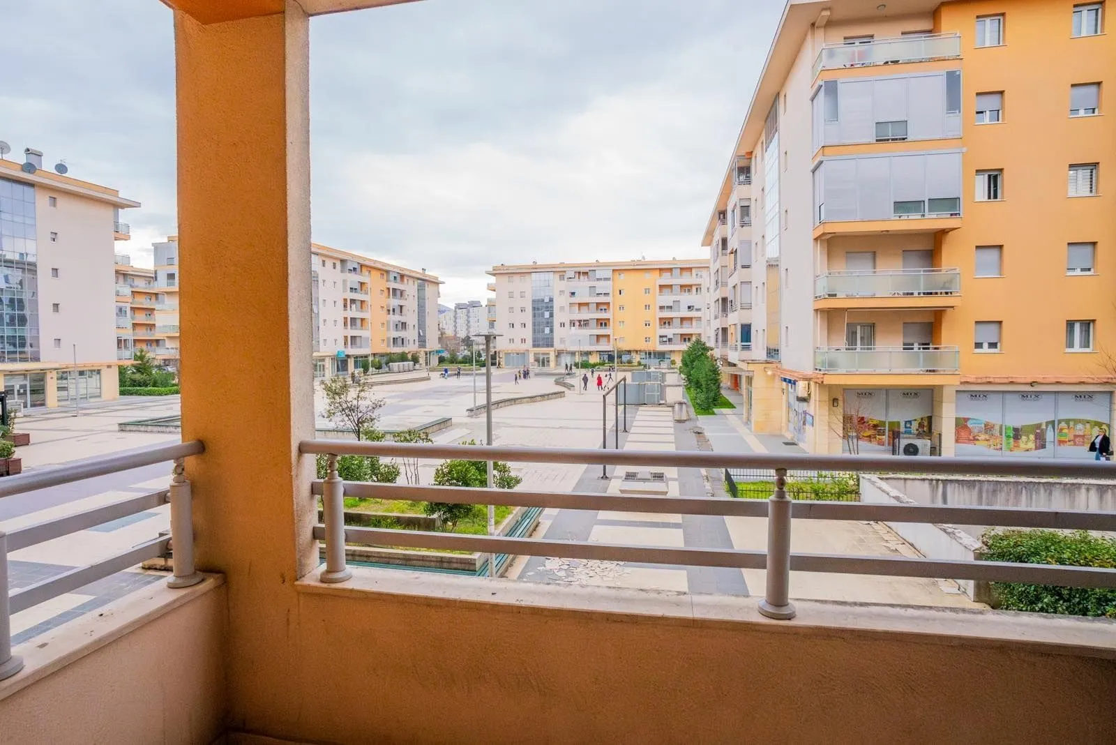 Pogled sa balkona na okolne stambene zgrade i popločani trg.