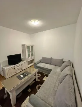 Dnevna soba sa sivom ugaonom garniturom, klub stolom i TV komodom. - image 3