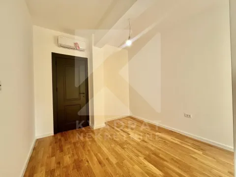 Prazna soba sa drvenim podom, klima uređajem i tamnim vratima. - image 7