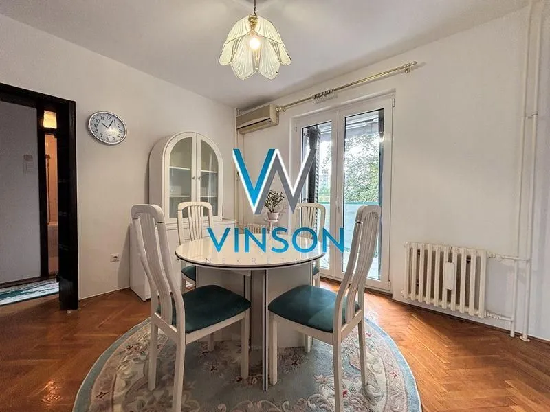 Trpezarija sa stolom, stolicama i vitrinom u stanu.