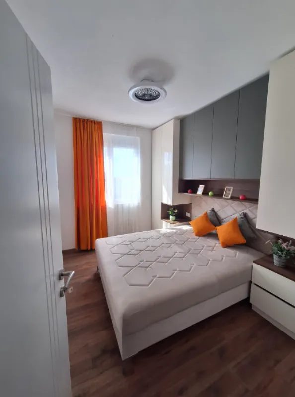 Bedroom with a double bed, fitted wardrobes and orange details.