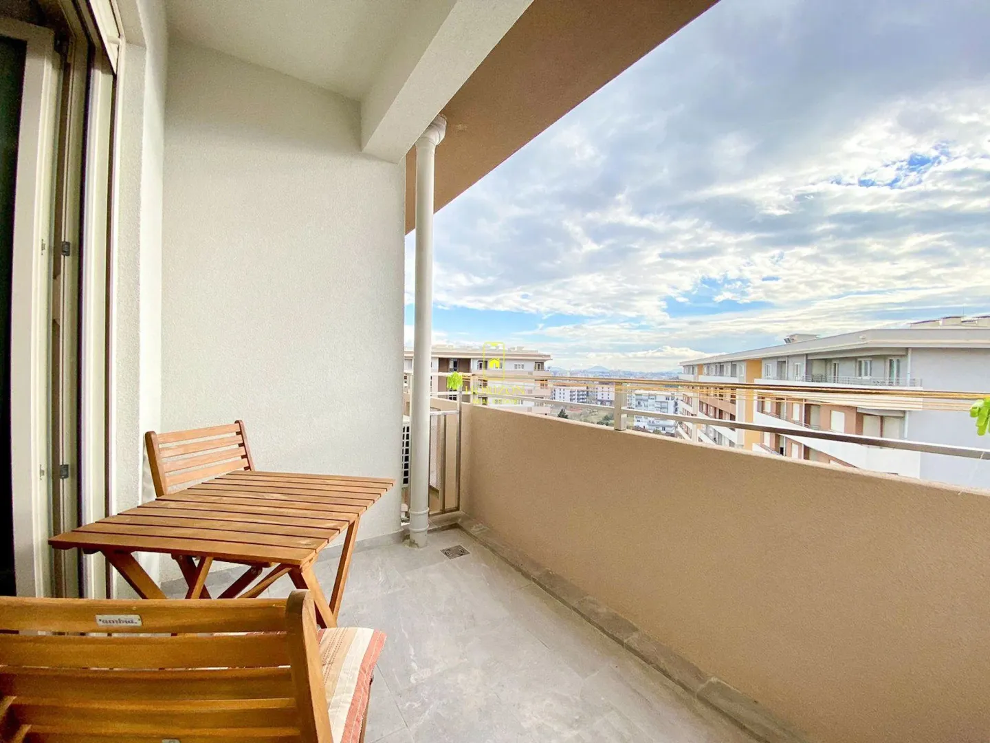 Spacious balcony with a wooden table and city views.