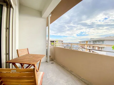 Spacious balcony with a wooden table and city views. - image 7