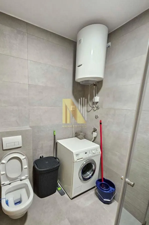 Modern bathroom with a walk-in shower, toilet, washing machine, and water heater.