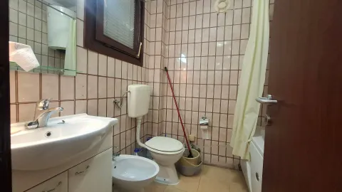 Manje kupatilo obloženo keramičkim pločicama sa umivaonikom, šoljom i kadom. - image 14