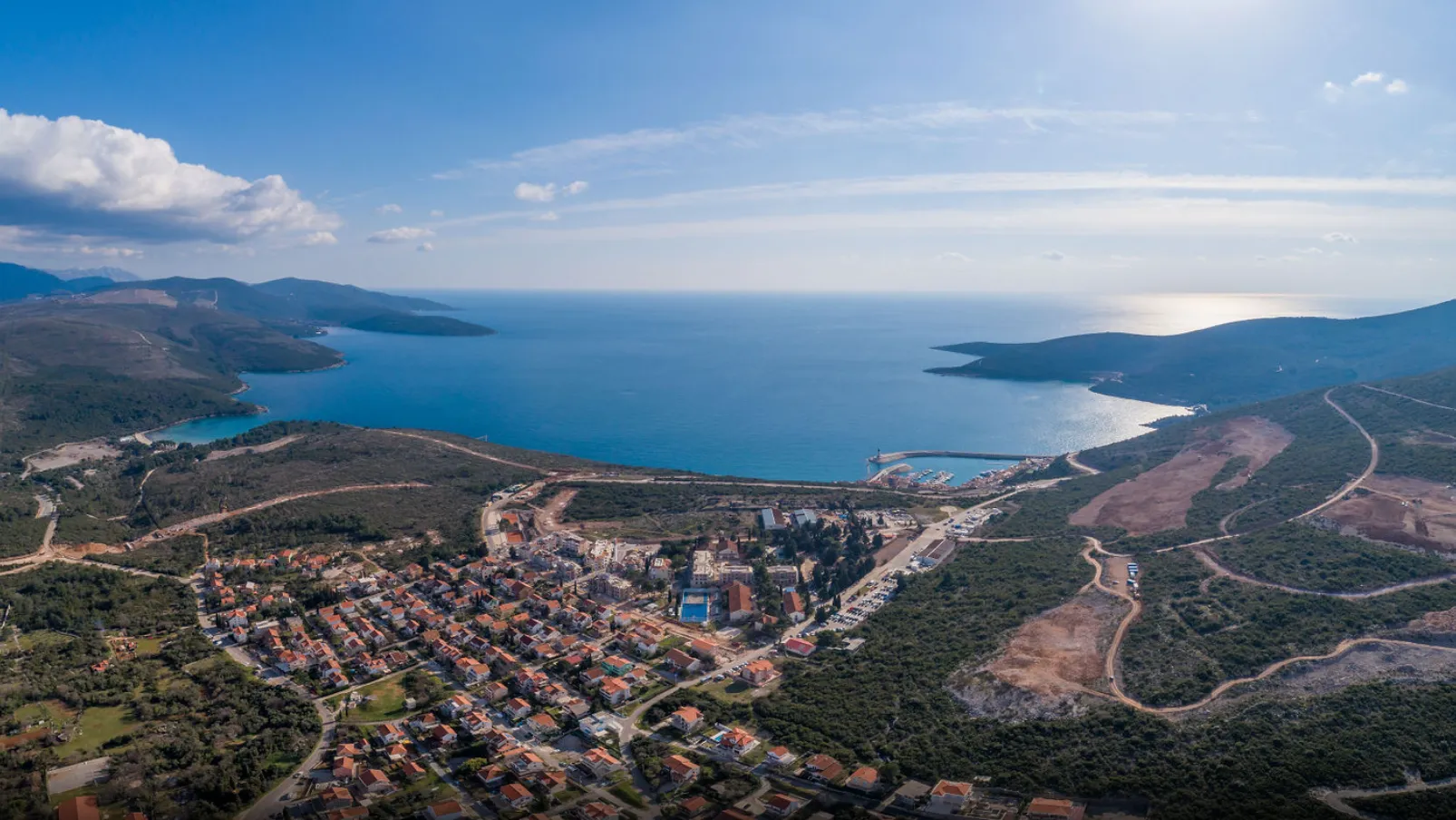 Panoramski pogled iz vazduha na priobalno naselje i otvoreno more.