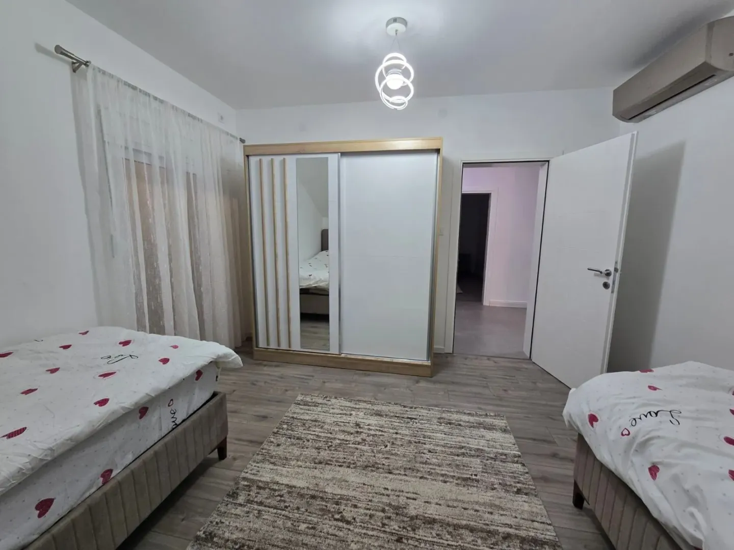 Spavaća soba sa dva kreveta, velikim plakarom i tepihom.