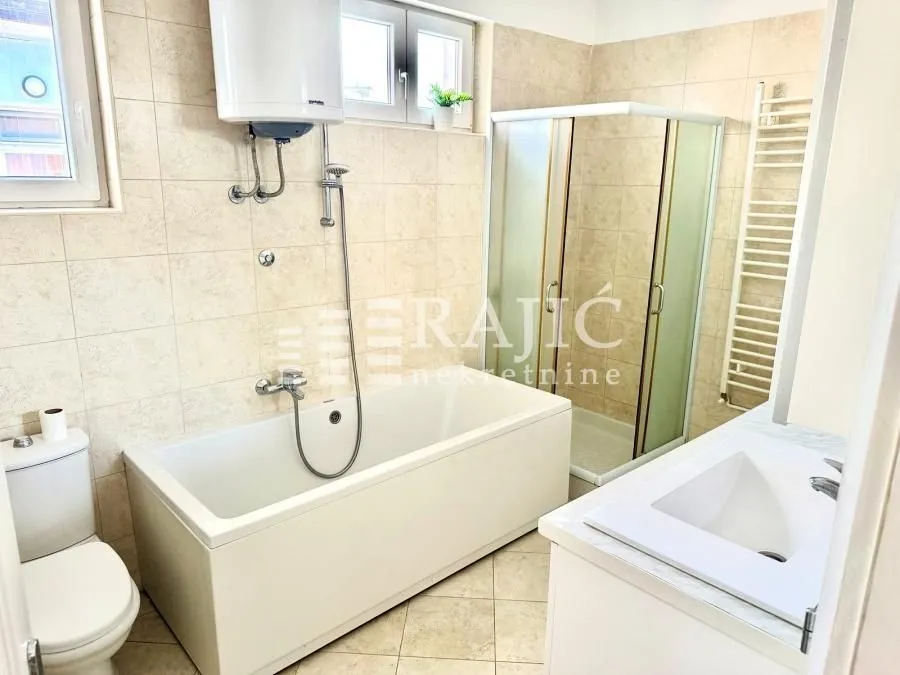 Bright bathroom with a bathtub, shower cabin, and white sanitaryware.