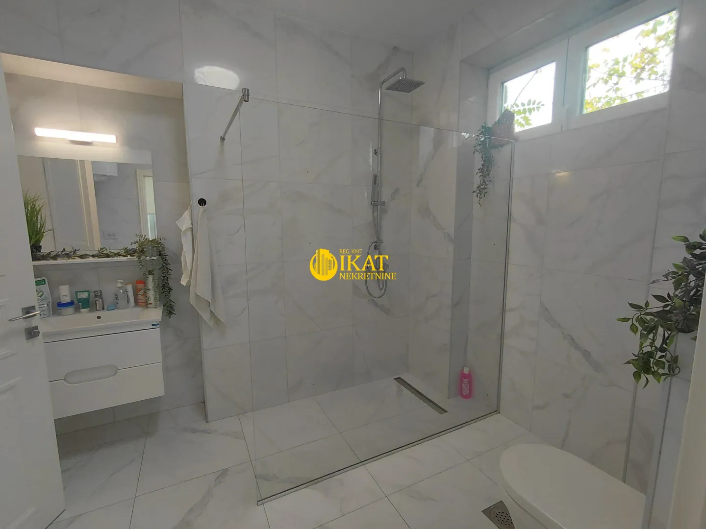 Modern bathroom with a walk-in shower, washbasin, and toilet.