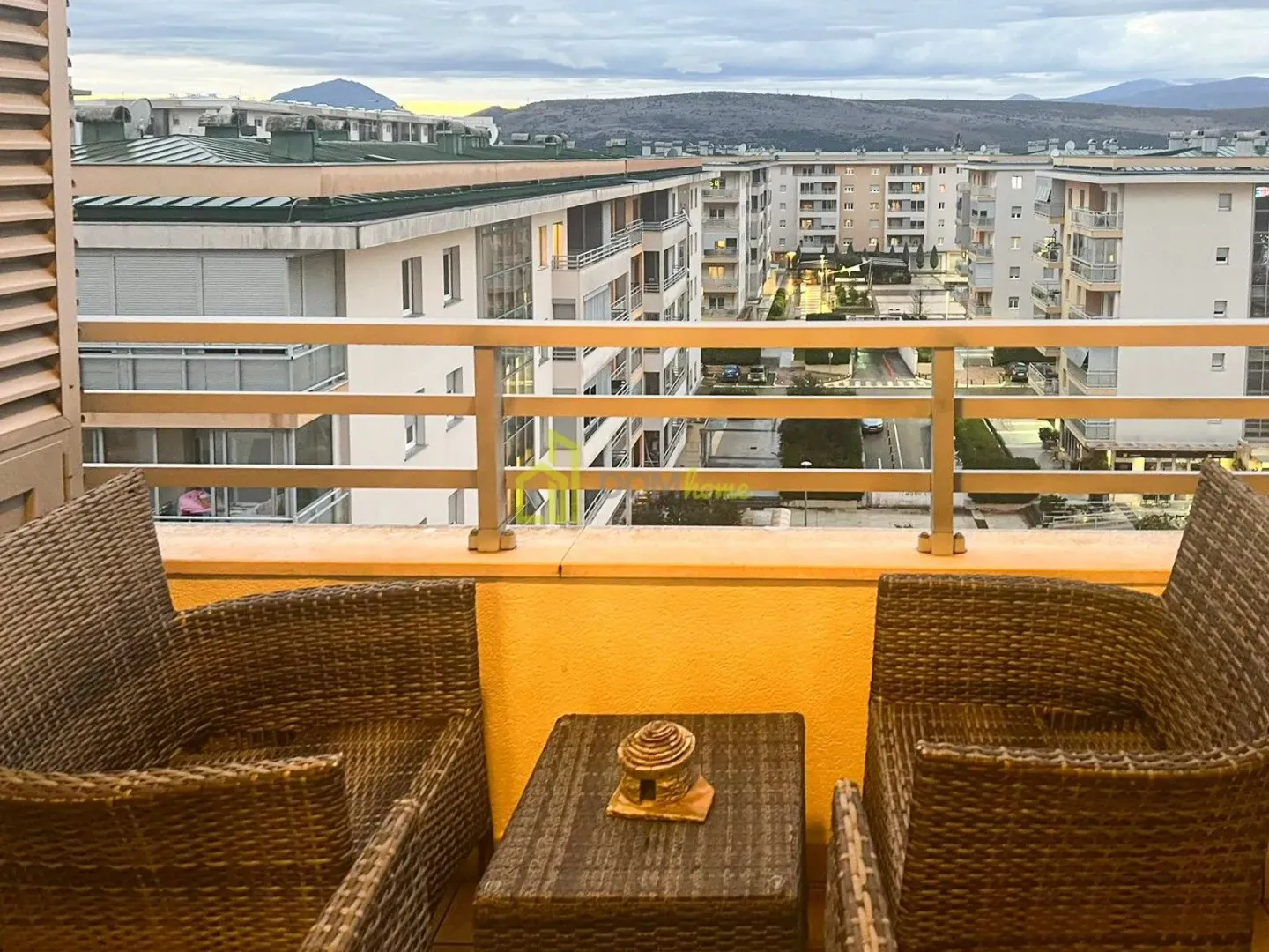 Namješten balkon sa garniturom za sjedenje i pogledom na naselje.