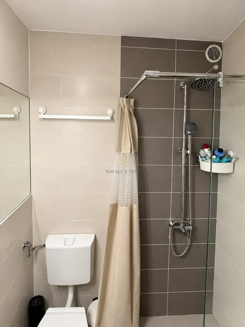 Kupatilo sa tuš kabinom, WC šoljom i ogledalom.
