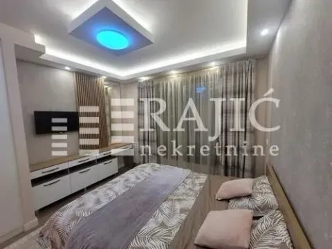 Furnished bedroom with a double bed, TV unit, and a dropped ceiling with lighting. - image 5