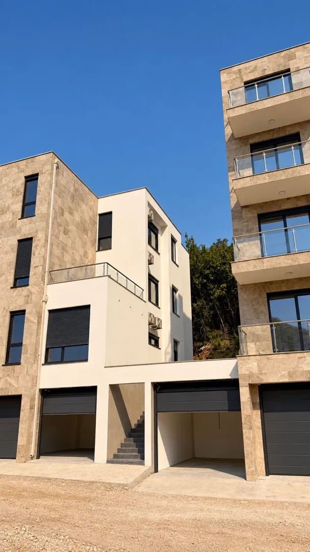Eksterijer modernih stambenih zgrada sa balkonima i garažama u prizemlju.