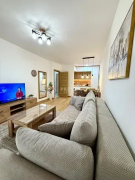 Spacious living room with a sofa and a view towards the dining area and kitchen. - image 4