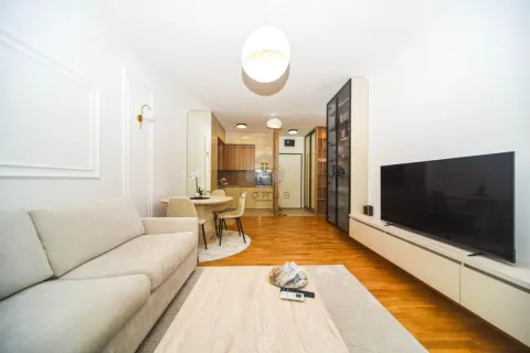 Living room with a sofa, TV, and an adjoining dining area. - image 4