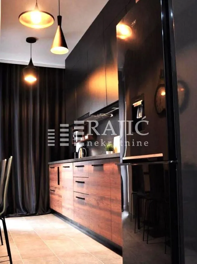Modern kitchen with dark cabinetry and built-in appliances.