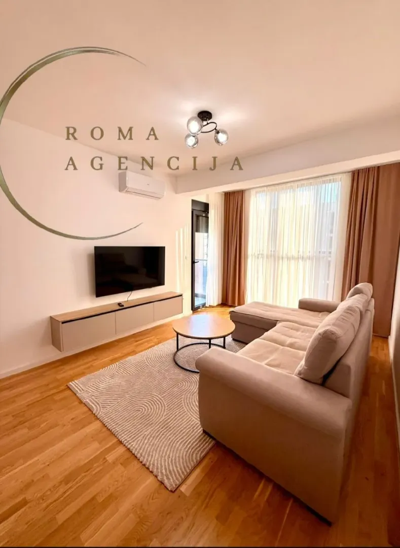 Bright living room with a corner sofa, television, and wooden flooring.