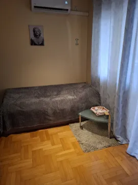Simple bedroom with a single bed, a small glass table, and air conditioning. - image 3