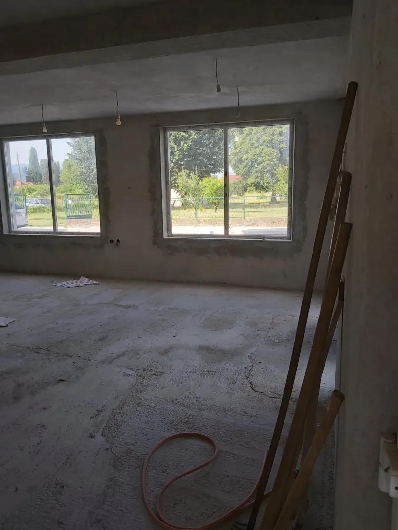 Spacious room in the rough construction stage with large windows.