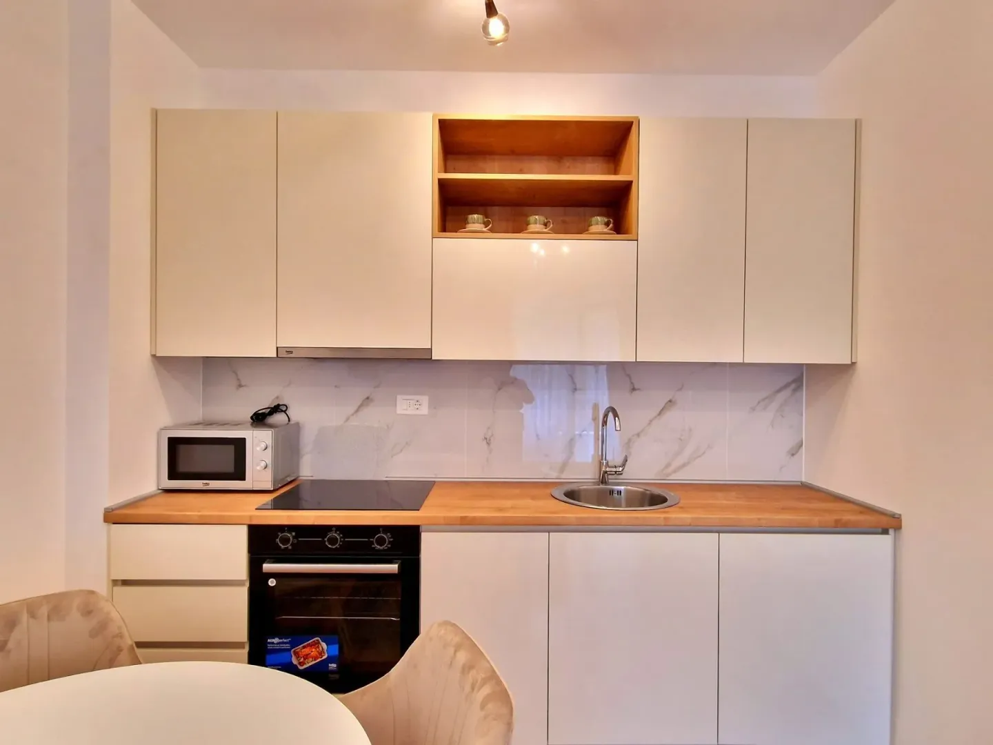 Modern kitchen equipped with white cabinets and a wooden countertop.