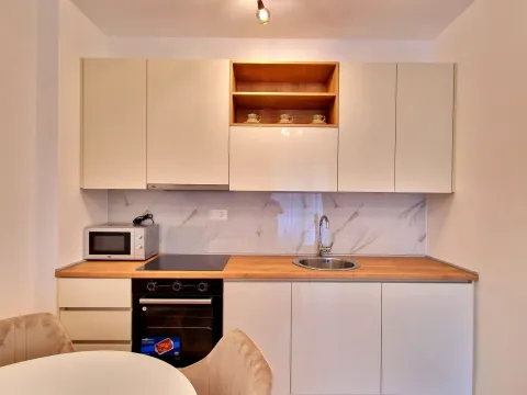 Modern kitchen equipped with white cabinets and a wooden countertop. - image 4