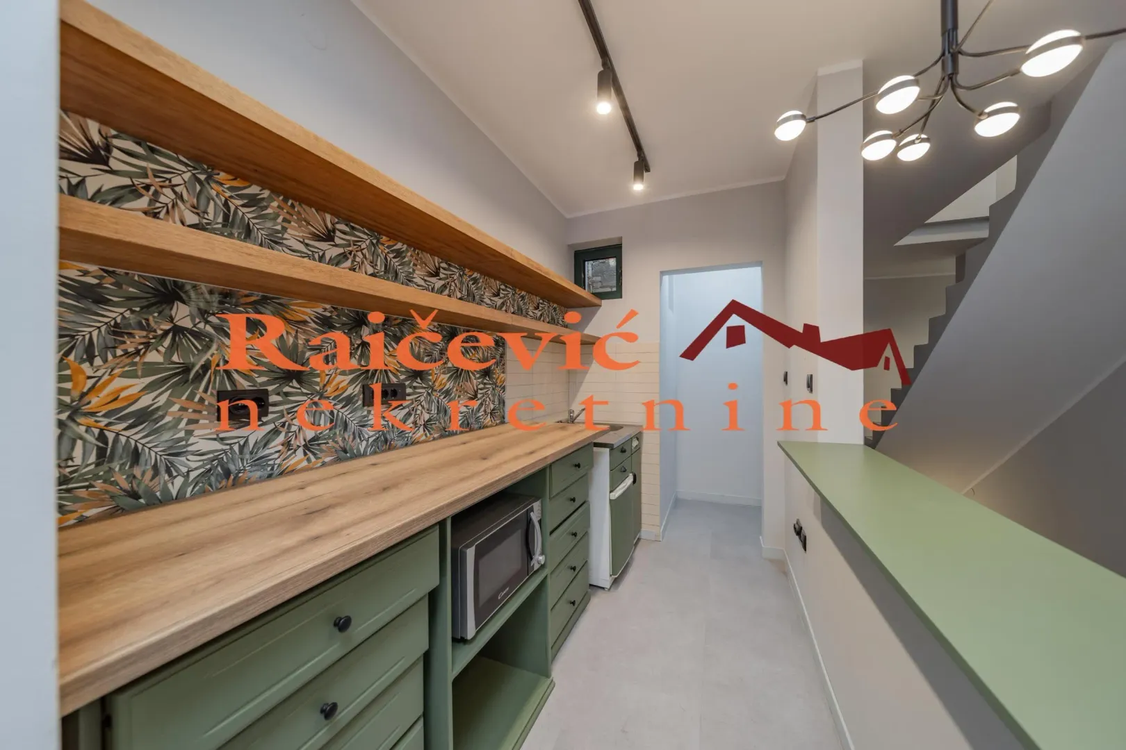 Modern kitchen with green cabinets and wooden shelves.