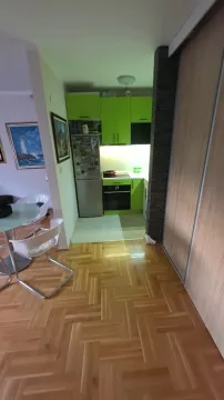 Smaller kitchen with green cabinets and parquet flooring in the hallway. - image 4