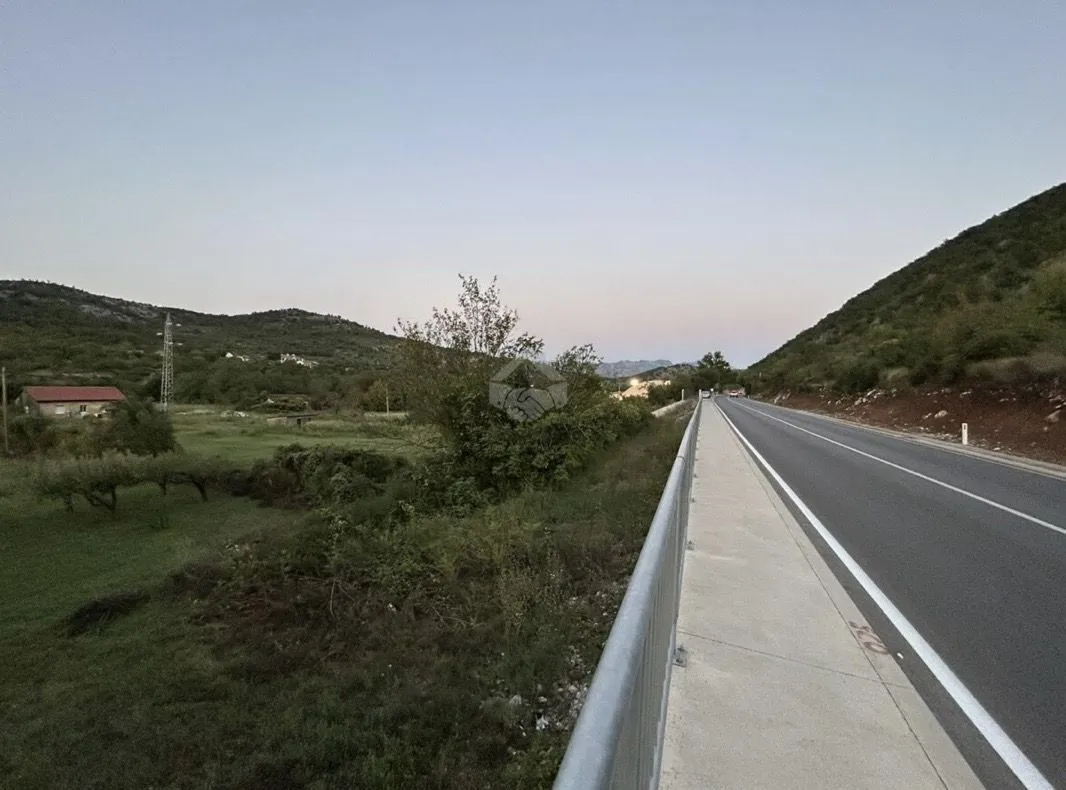 Pogled na zemljište pored puta sa okolnim brdima.