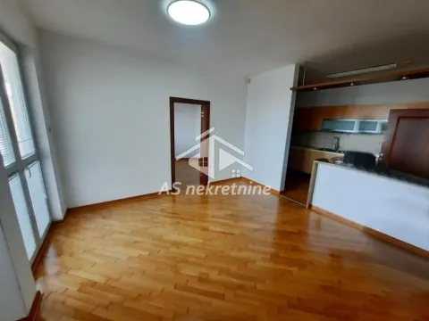 Prazna dnevna soba sa drvenim parketom i otvorenim prolazom ka kuhinji. - image 3
