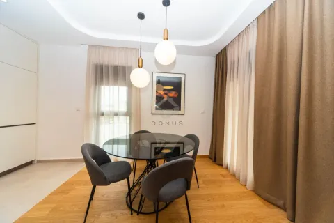 Trpezarija sa okruglim stolom, sivim stolicama i modernim visilicama. - image 4