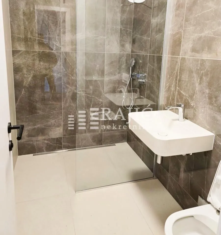 Modernly equipped bathroom with a walk-in shower and washbasin.