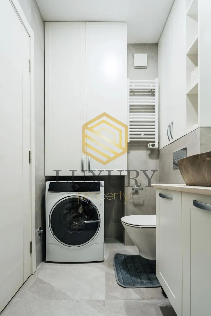 Modern bathroom with a washing machine, built-in cabinets, and a toilet.