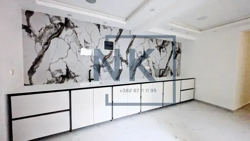 Modern kitchen with white cabinetry and a marble backsplash.